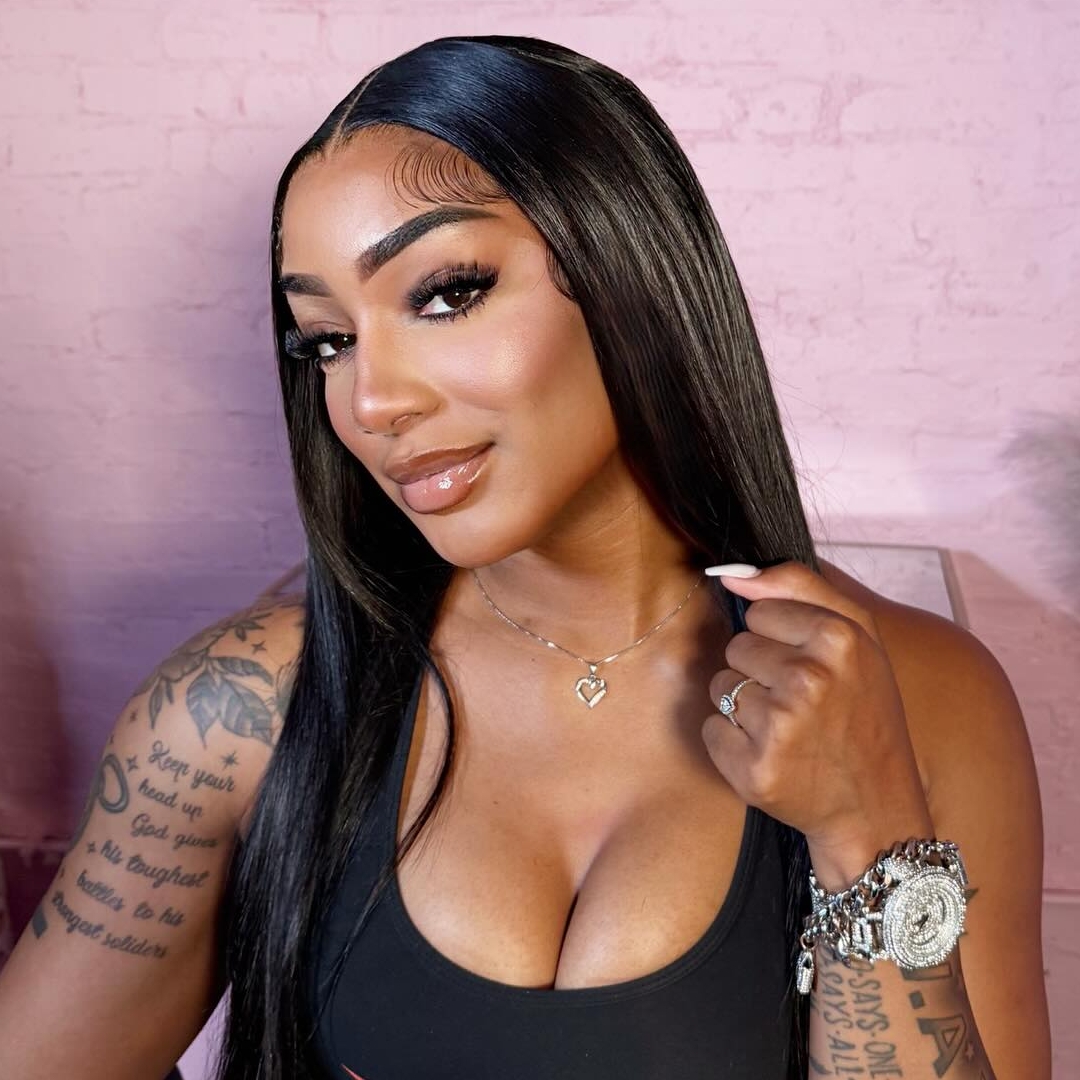 Close-up portrait of reality television personality and model Jada Thorpe with sleek, long black hair, wearing a black tank top, a sparkly watch, and a heart pendant necklace, with a large tattoo visible on her upper arm.