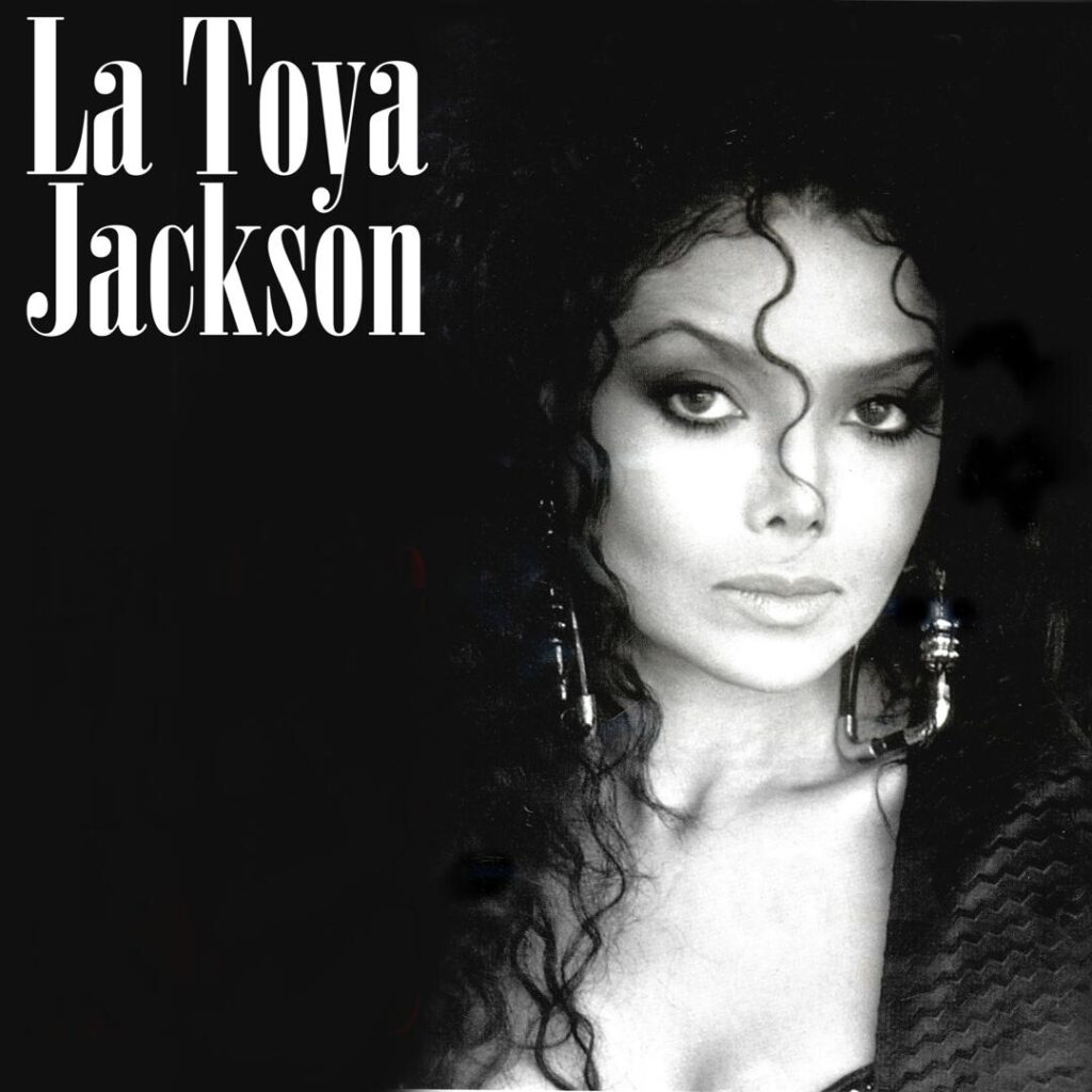 Black-and-white promotional portrait of singer La Toya Jackson featuring curly hair, dynamic tendrils framing her face, dramatic drop earrings, and bold white typography spelling her name in the upper left corner.