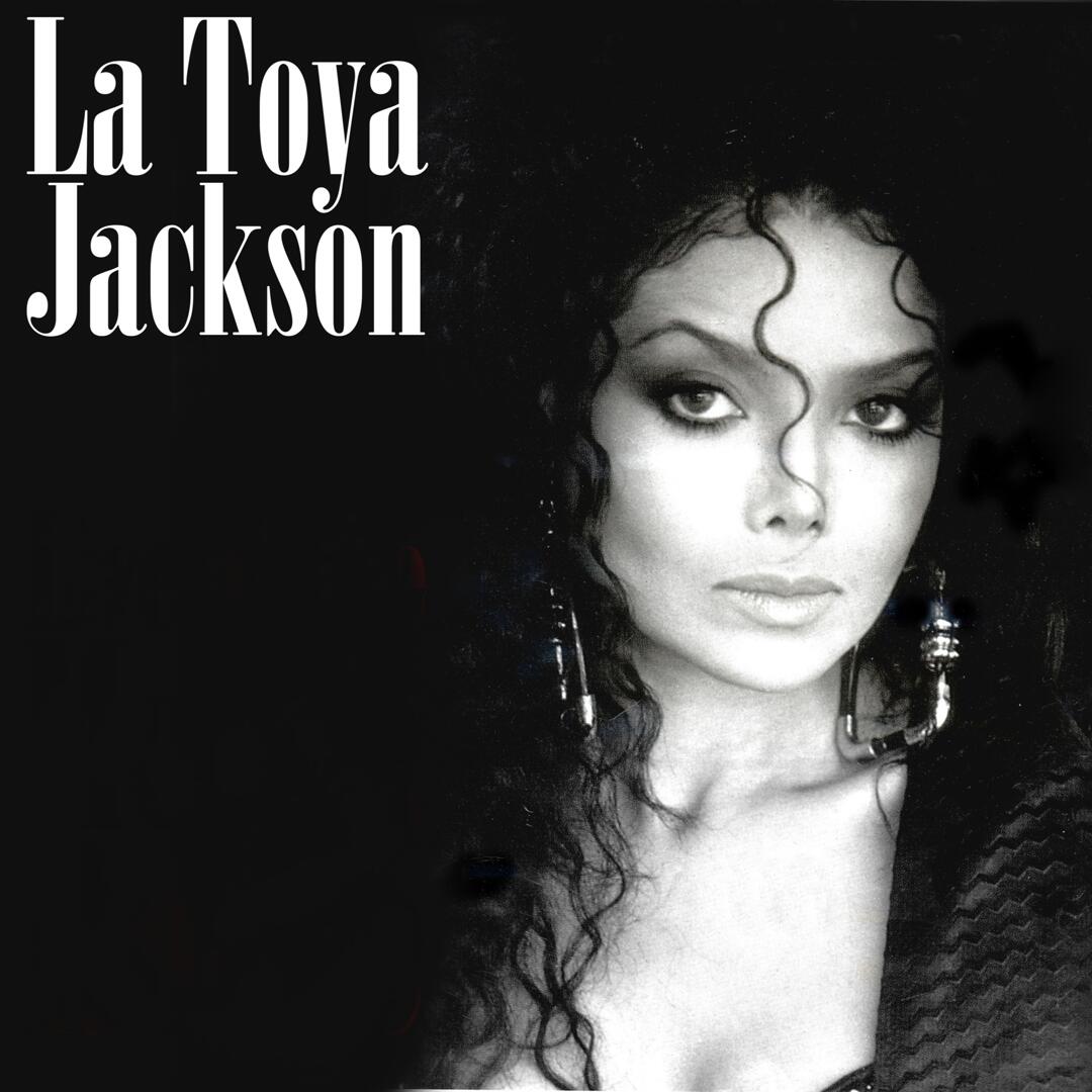 Black-and-white promotional portrait of singer La Toya Jackson featuring curly hair, dynamic tendrils framing her face, dramatic drop earrings, and bold white typography spelling her name in the upper left corner.